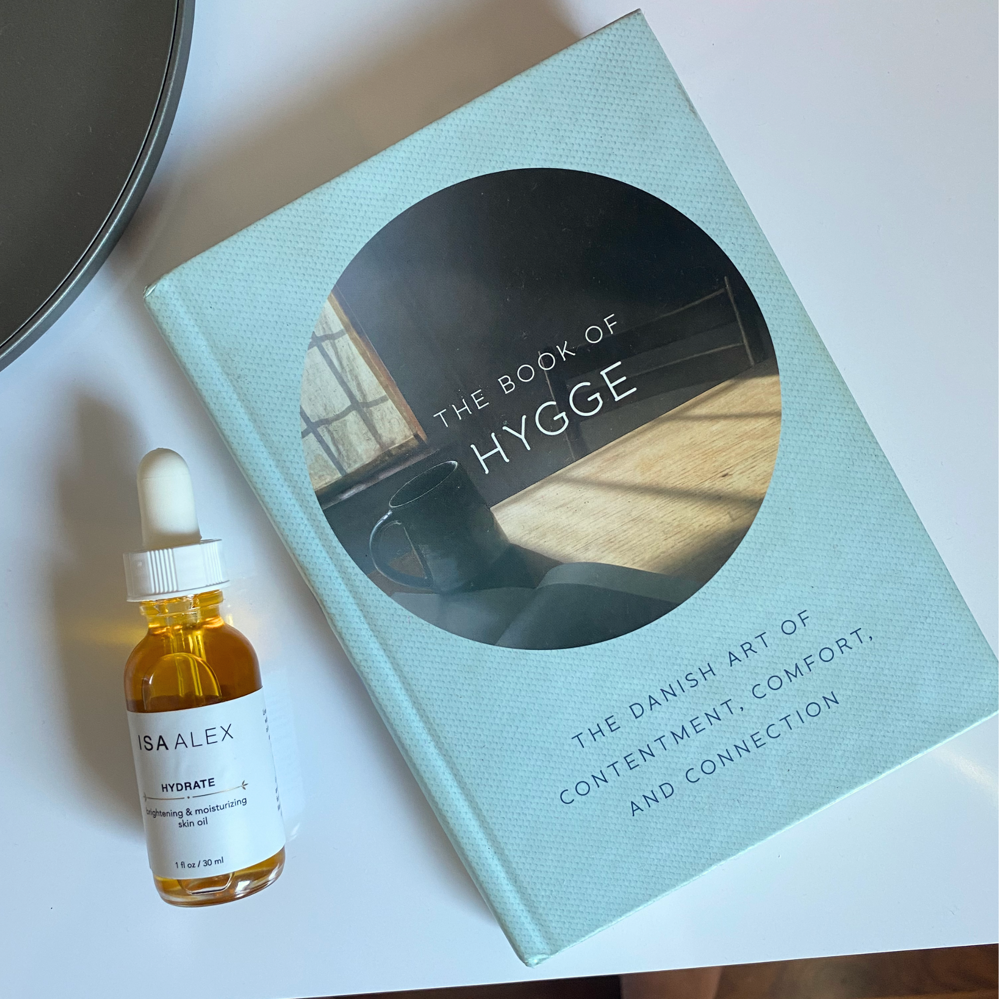 isa alex hydrate face oil on nightstand with the book of hygge the danish concept of contentment