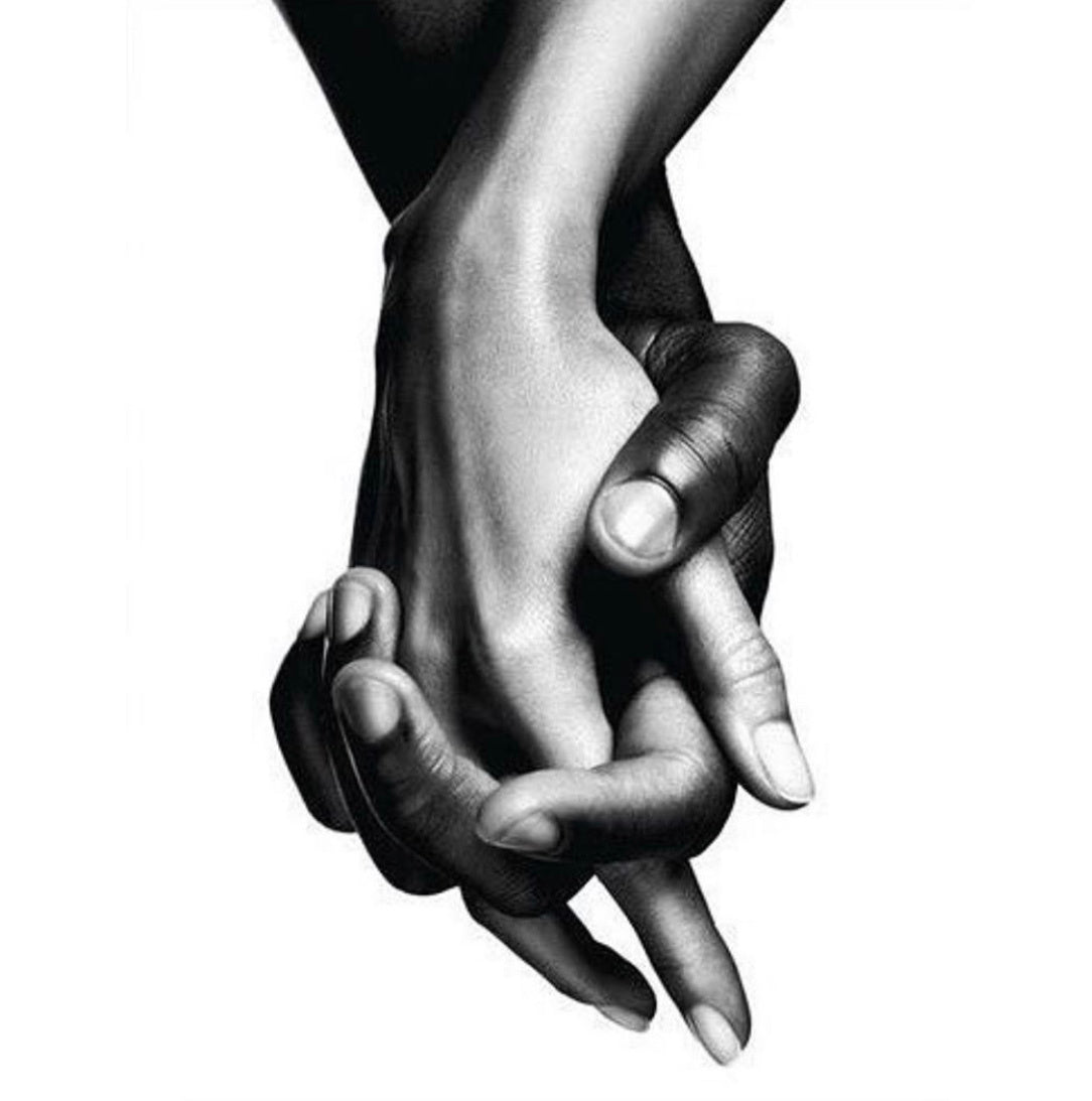Black and white photo closeup of a Black and White hands interlaced in support of Black Lives Matter movement.